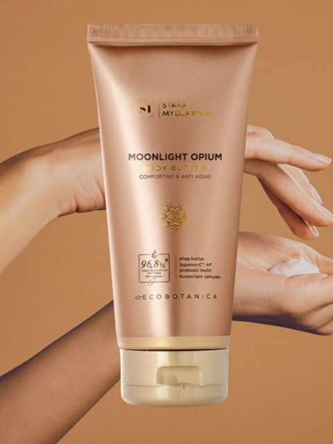 Masło do ciała Moonlight Opium 170 ml – Stara Mydlarnia, w tle dłonie z masełkiem do ciiała